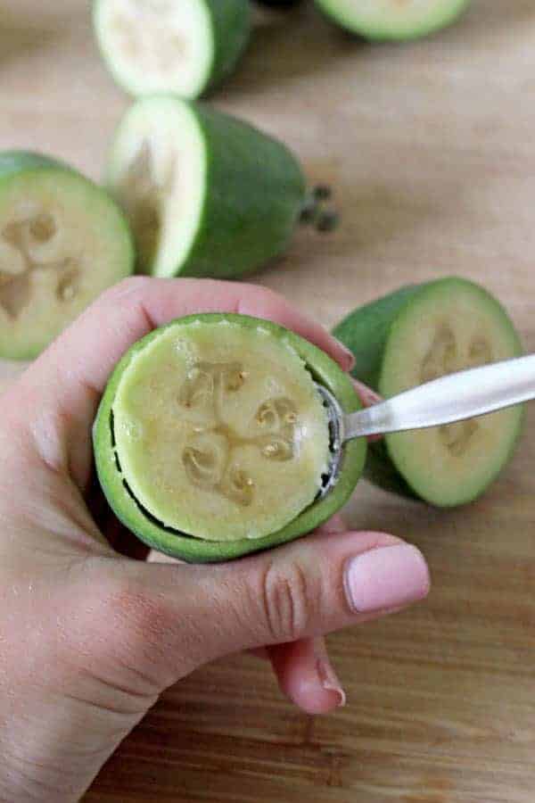 Scooping flesh out of feijoa with a spoon