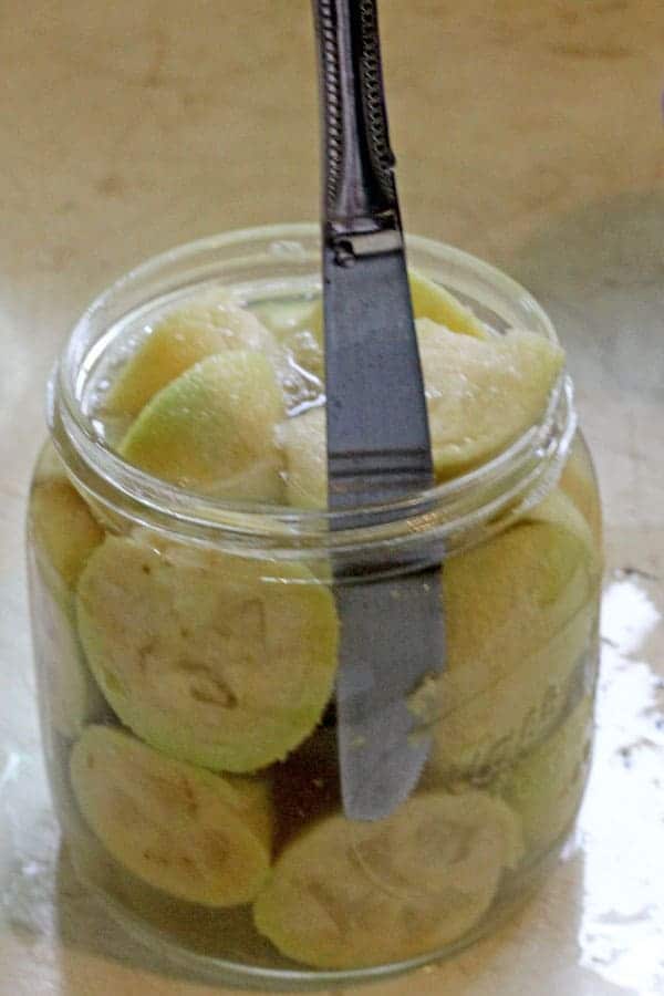 Using a knife to remove air bubbles in the jar of canned feijoas
