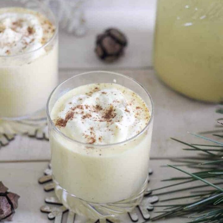 Glasses of eggnog on a tray with pine needles and snowflakes