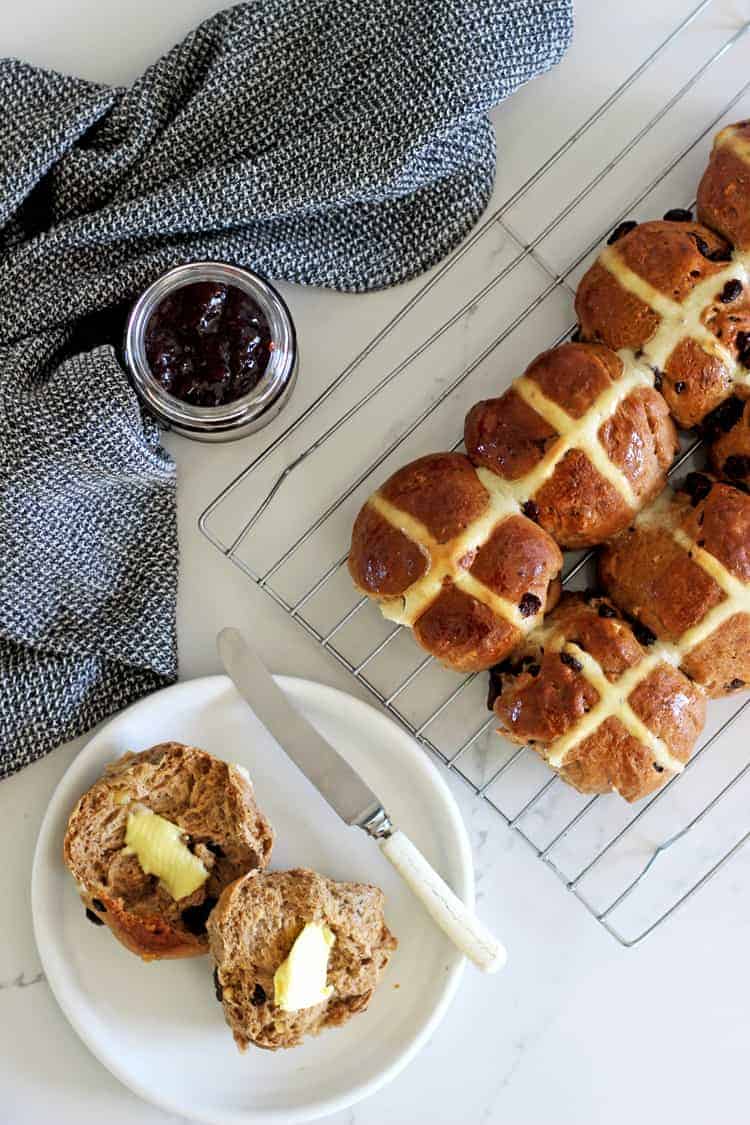 Tray of hot cross buns with jar of jam and tea towel