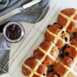 Tray of hot cross buns with jar of jam and tea towel