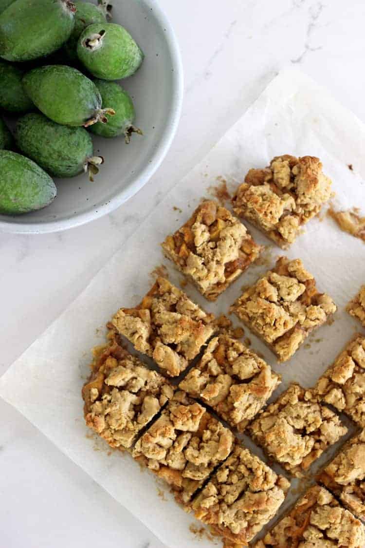 Feijoa crumble slice cut into pieces on a white marble background