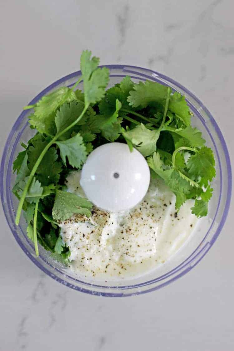 Food processor bowl with cilantro and yoghurt dressing ingredients