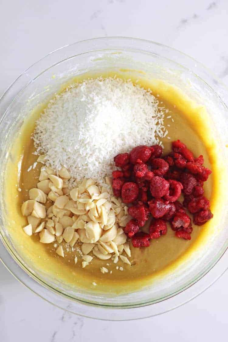 Mixing bowl with blondie batter and raspberries, white chocolate and coconut