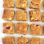 Close up of raspberry and white chocolate blondies on white background