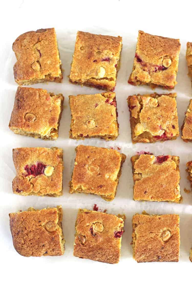Close up of raspberry and white chocolate blondies on white background