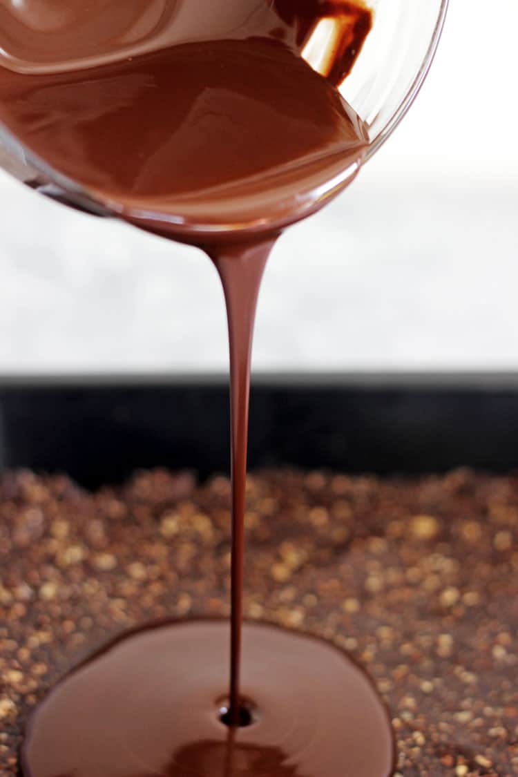 Melted chocolate being poured onto mocha energy bite slice