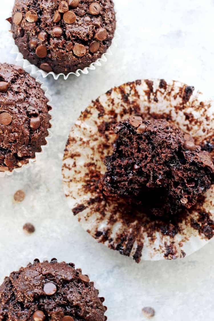 Overhead shot of double chocolate muffins on a white marble background, one split in half