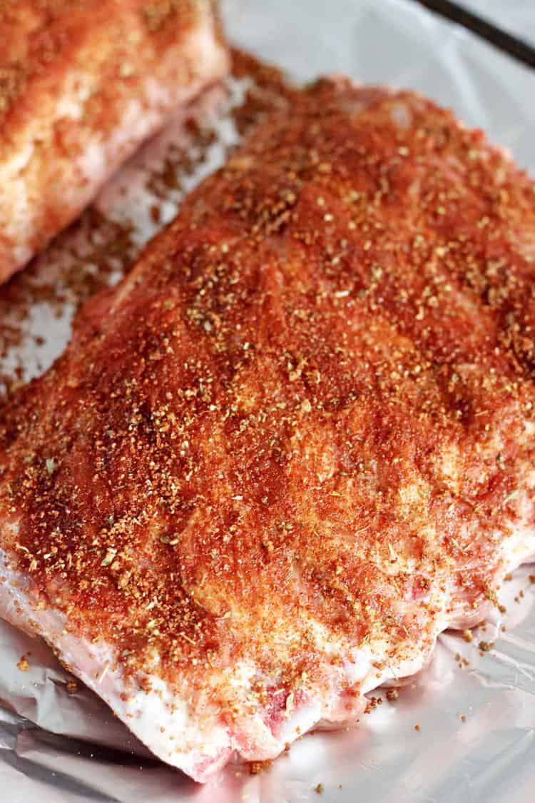 Rack of ribs on a baking tray covered with BBQ spice rub