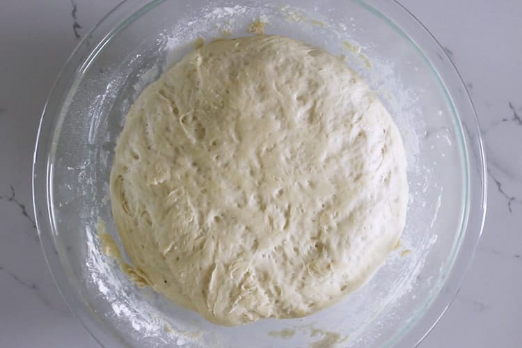 Risen bread dough in glass bowl