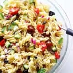 Glass bowl of Greek pasta salad on white background