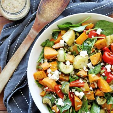 Roast Vegetable Salad on wooden table with serving spoon and dressing