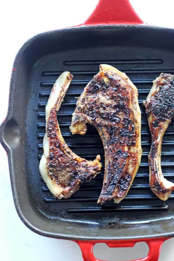 Lamb chops covered in herb marinade in a grill pan