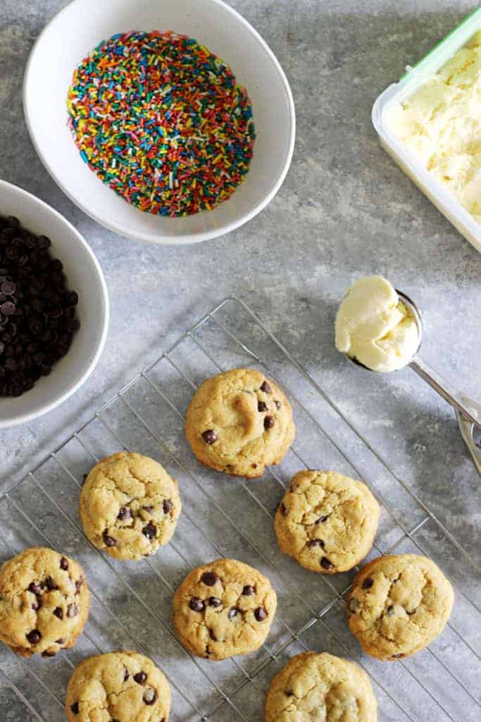 Tray of cookies with sprinkles and chocolate chips in bowls and a scoop of vanilla ice cream