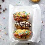 Container with 3 ice cream sandwiches covered in chocolate chips and sprinkles