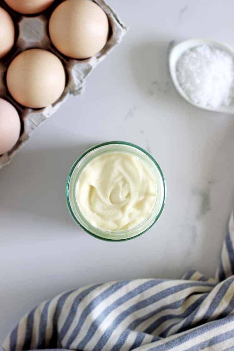 Overhead of jar of homemade mayo with eggs and salt in background