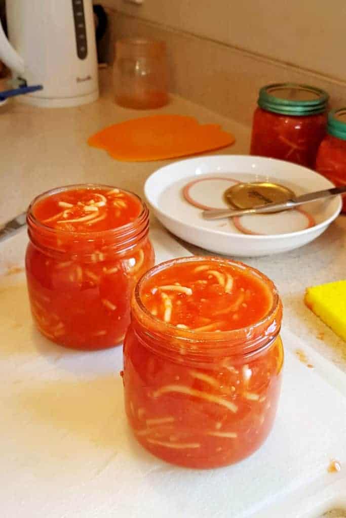 2 jars of spaghetti with seals in background and more jars