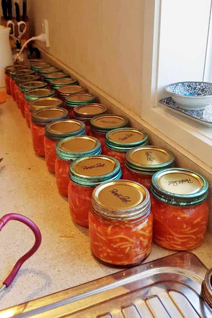 Line up of filled and sealed jars of homemade spaghetti