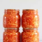 4 jars of homemade bottled spaghetti on a grey background