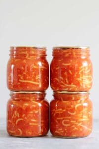 4 jars of homemade bottled spaghetti on a grey background