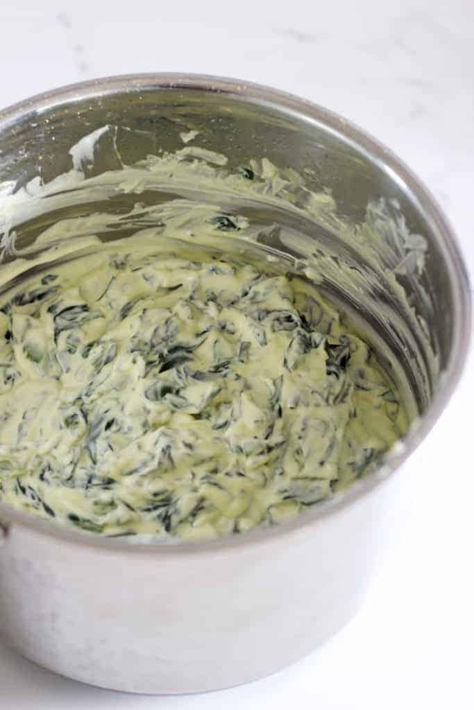 Pot with cheesy spinach dip for cob loaf