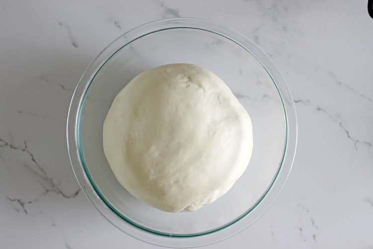 Bread dough rising in a glass bowl