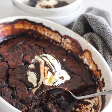 Chocolate self saucing pudding in white dish with bowl served up beside it