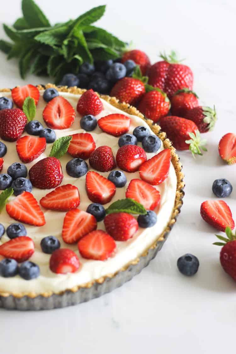 Summer berry tart on white marble background with strawberries and blueberries