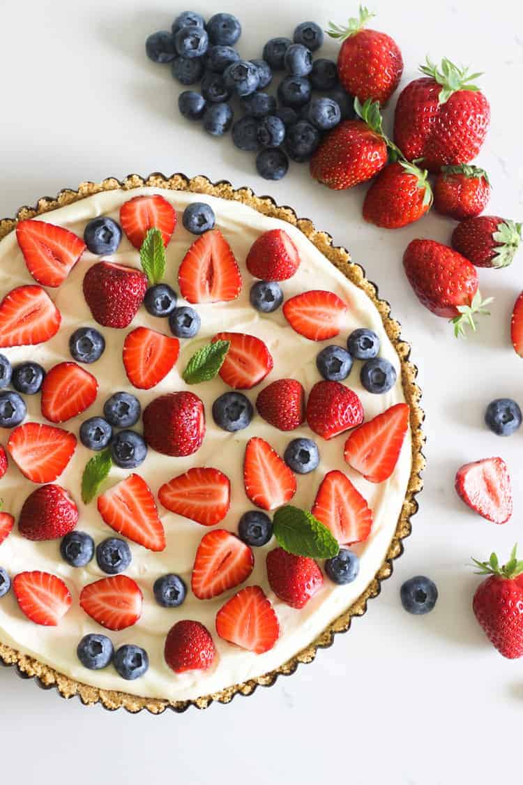Summer berry tart on white marble background with strawberries and blueberries