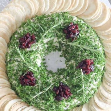 Christmas cheese ball wreath on serving plate with crackers and knife
