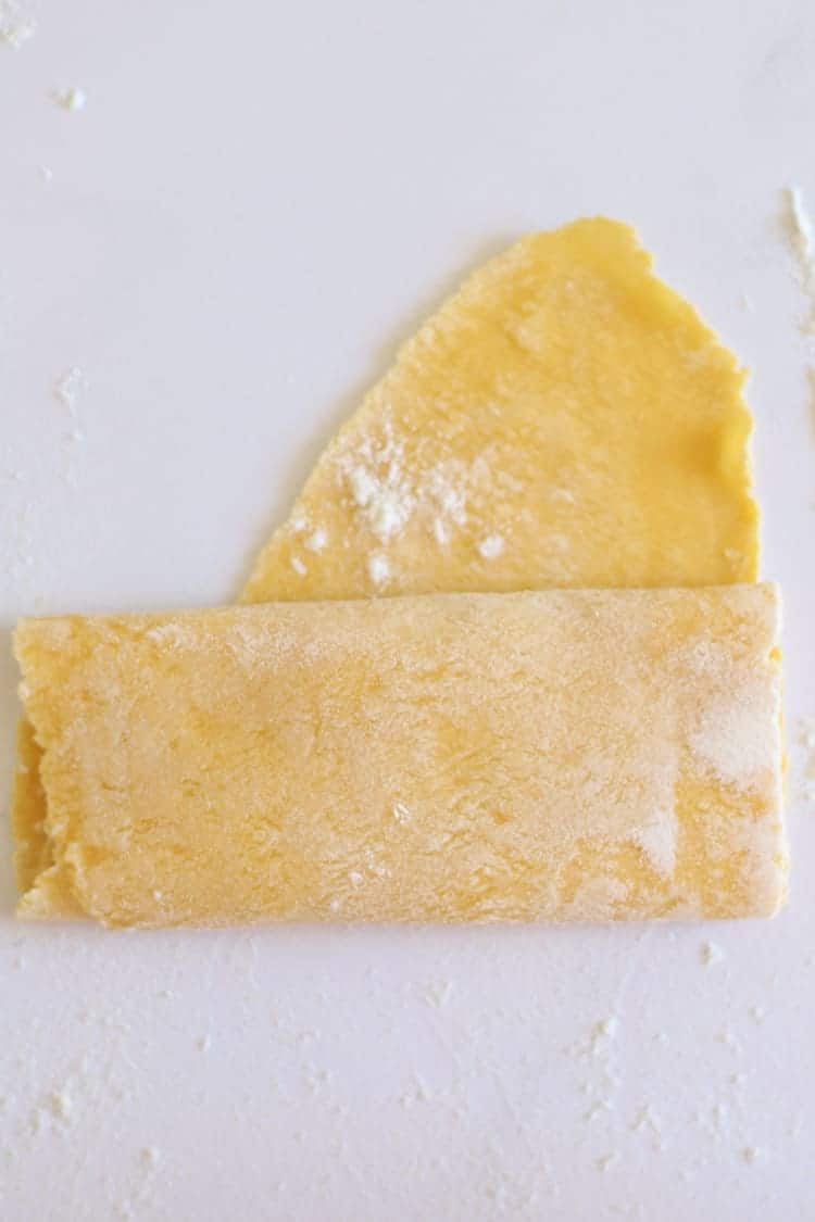 Rolled piece of pasta dough being folded to cut