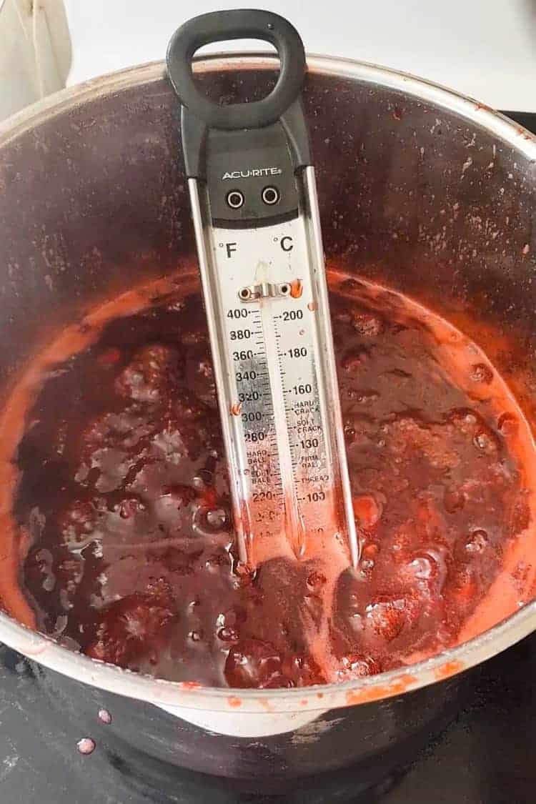 Pot of strawberry jam on stove with candy thermometer