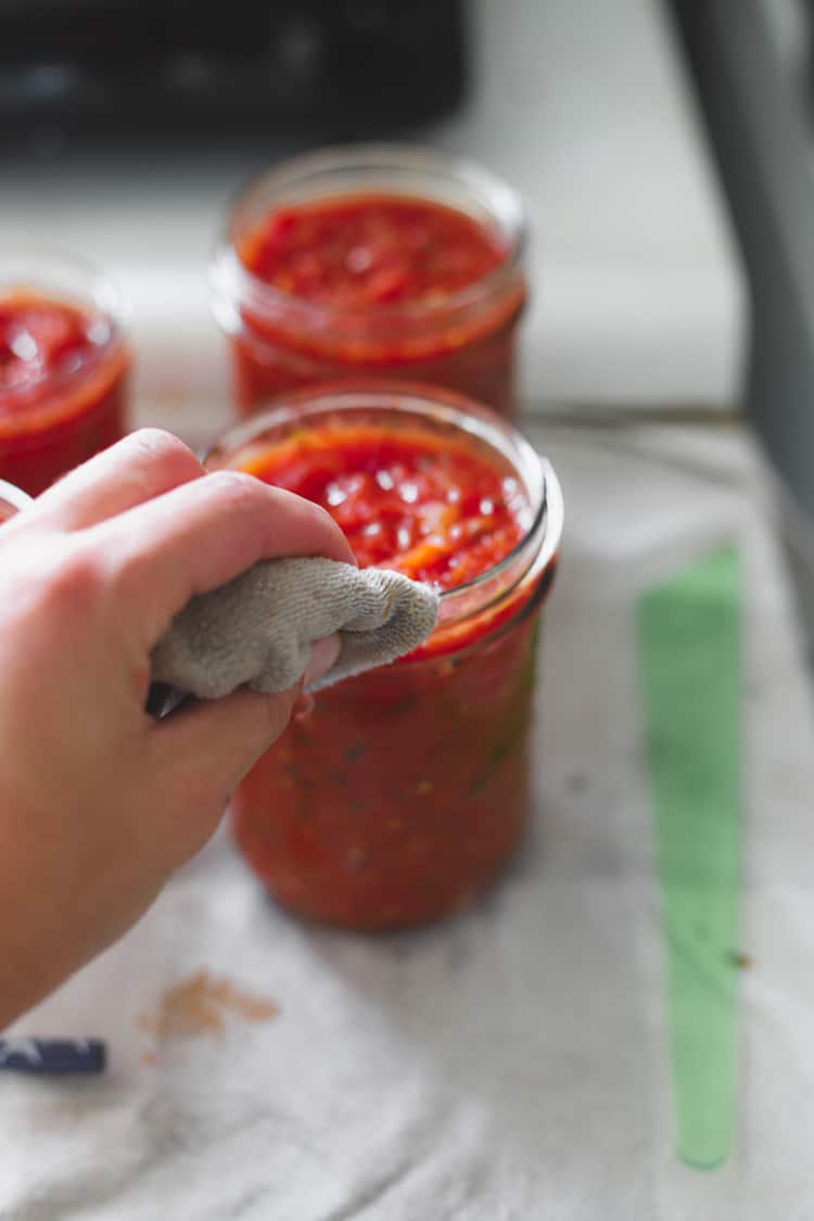 Wiping rim of jar of tomato salsa