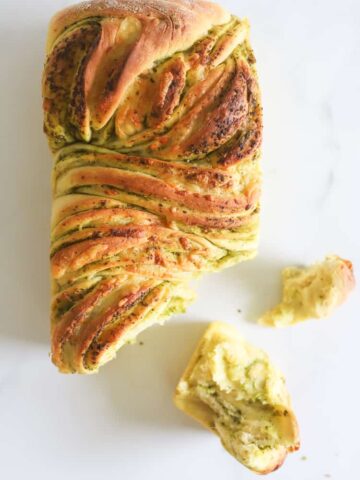 Loaf of pull apart bread with piece pulled off on white background