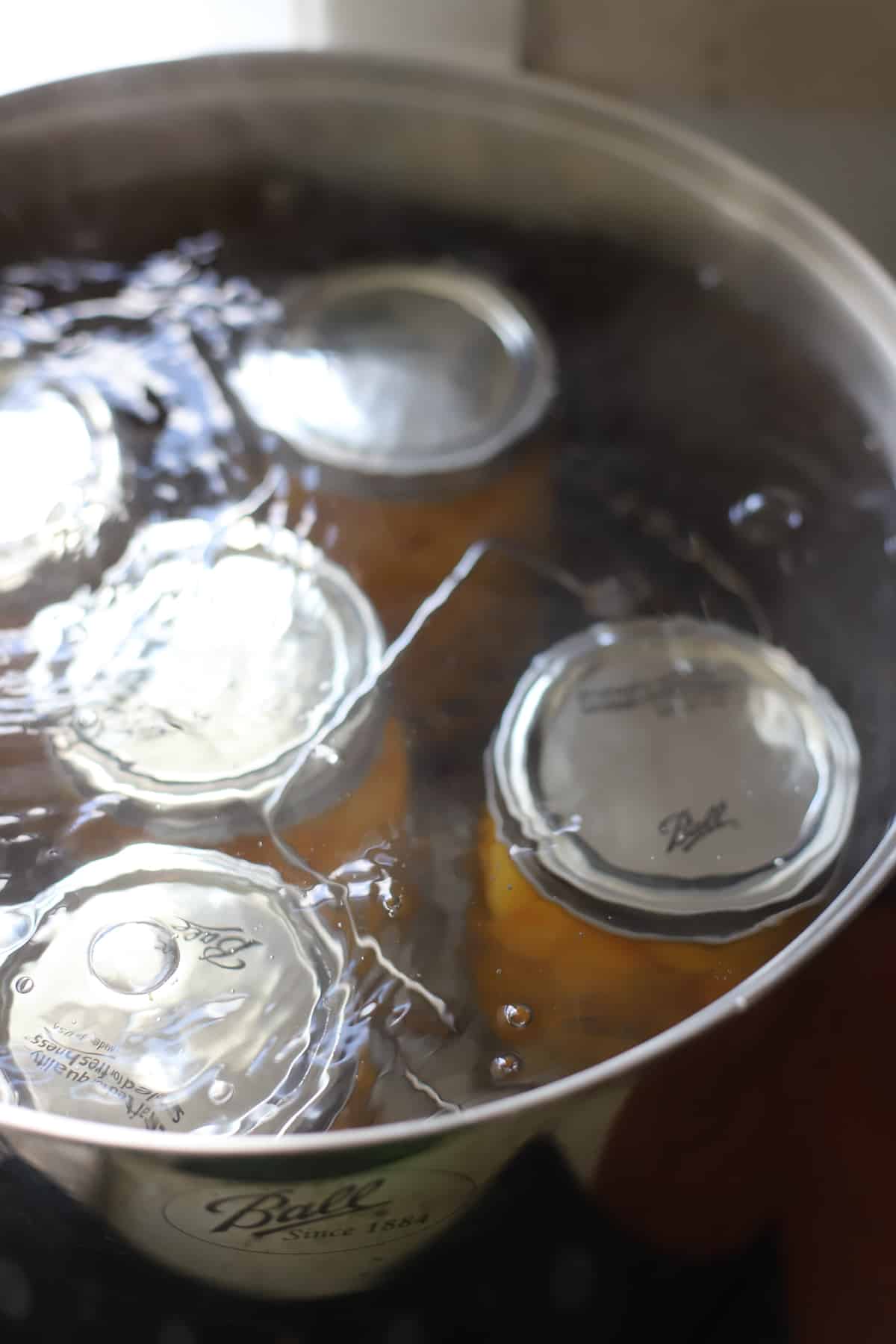 Jars of peaches being processed in a water bath canner
