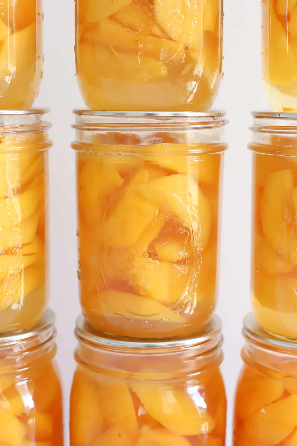 Jars of bottled peaches on a white background.
