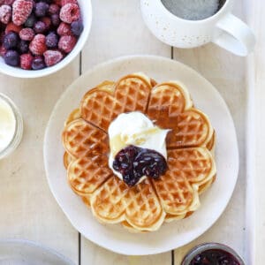 Plate of waffles topped with berry sauce and cream