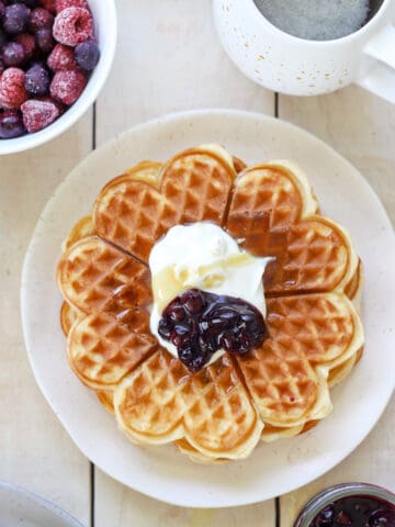Plate of waffles topped with berry sauce and cream