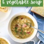 Bowl of bacon bone and vegetable soup on table with slice of buttered bread with text overlay