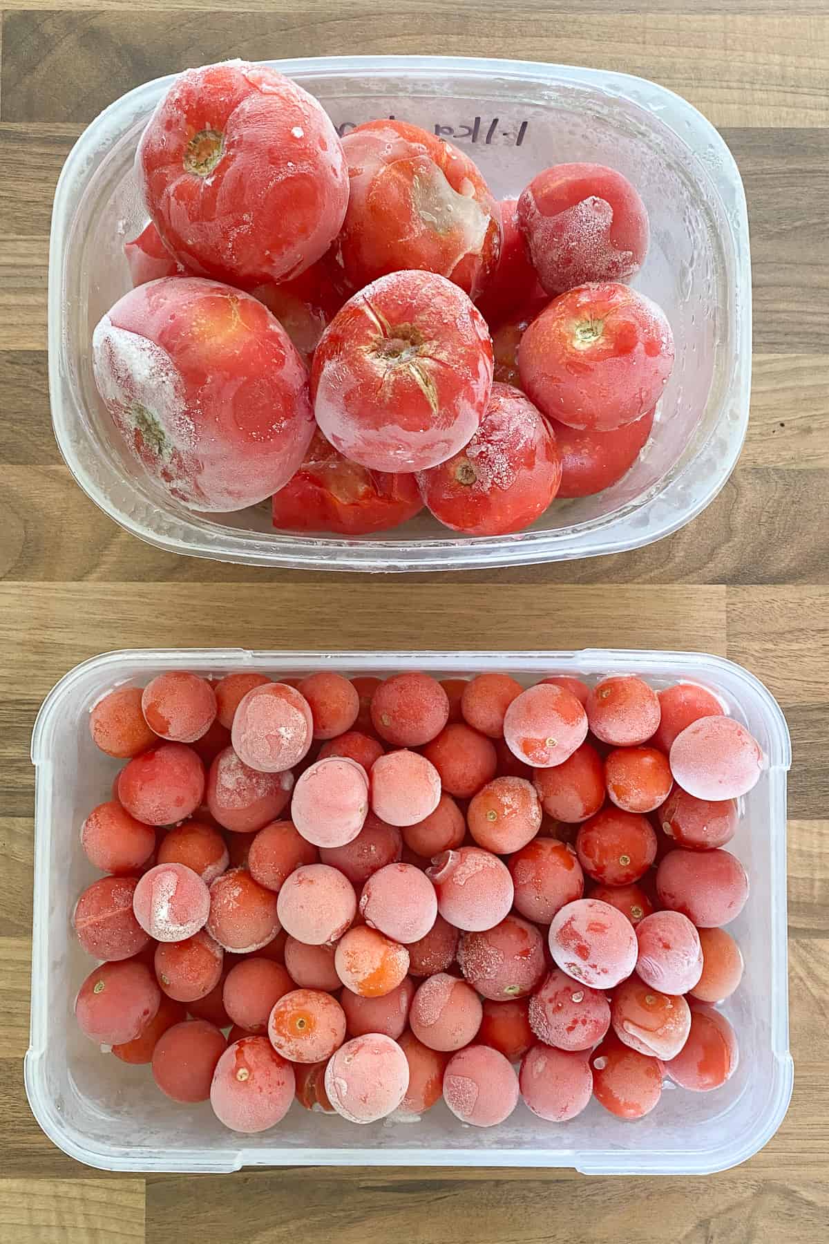 Container of frozen cherry tomatoes and one container of frozen whole tomatoes