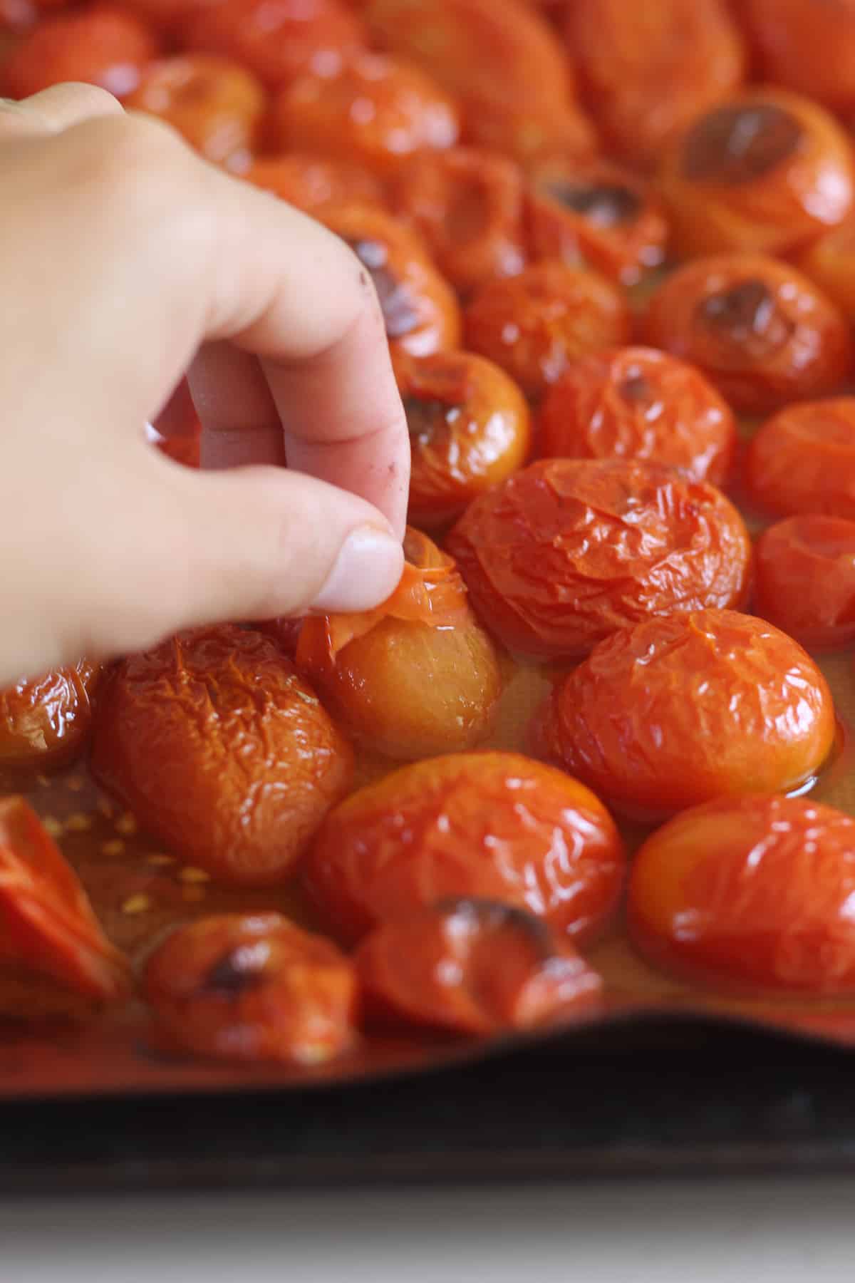 Hand peeling skins off grilled tomatoes
