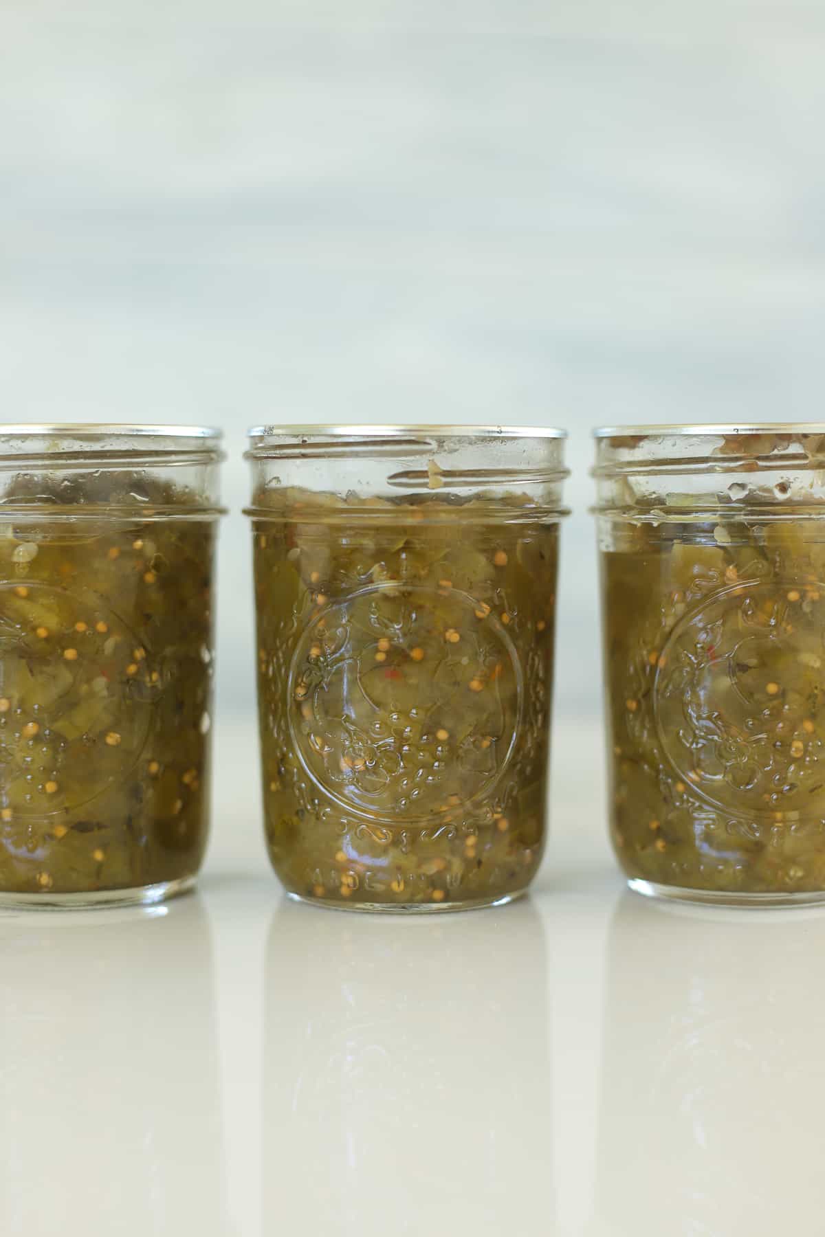 3 jars of zucchini relish on a white table