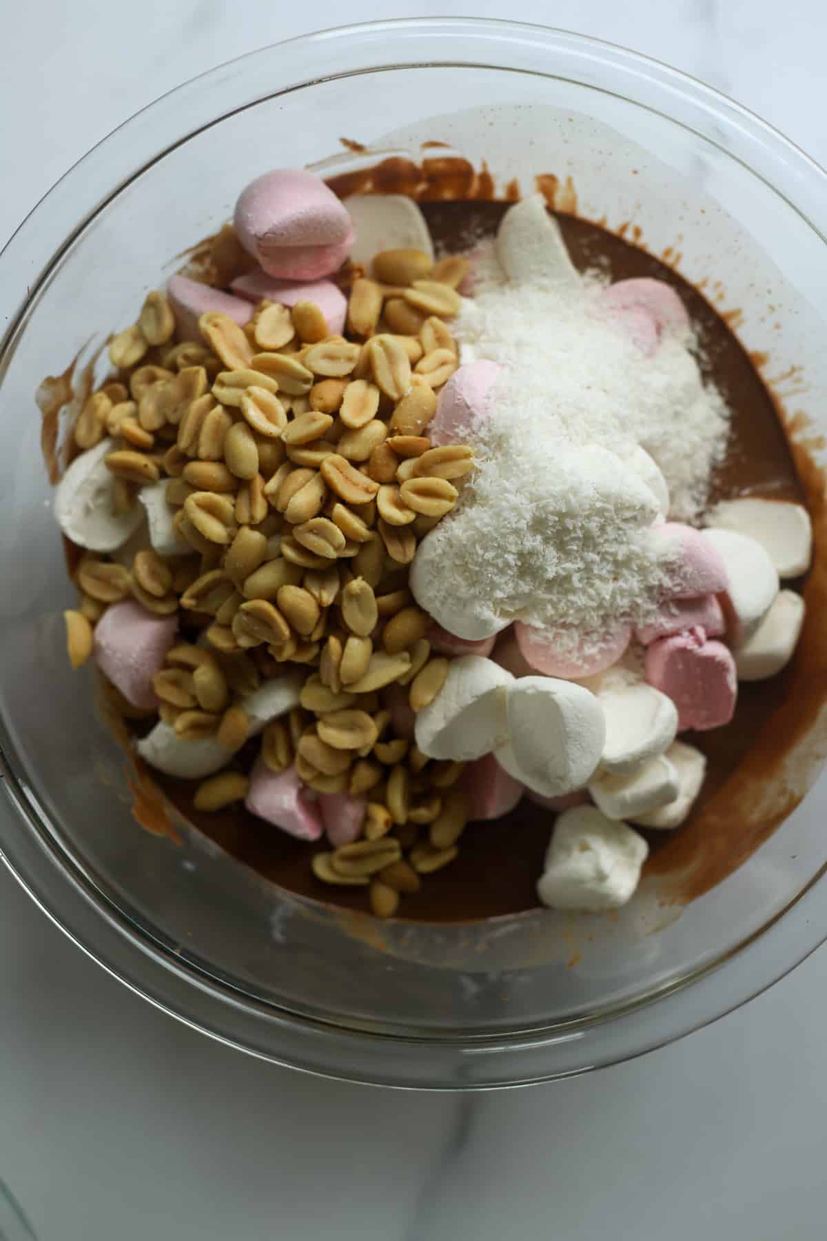 Bowl of melted chocolate, coconut oil, peanuts, coconut and marshmallows for rocky road
